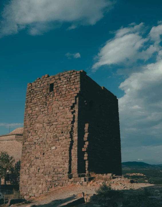 a small stone tower made of bricks sits on a hilltop