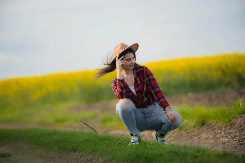 a woman sitting on a green field talking on a cellphone