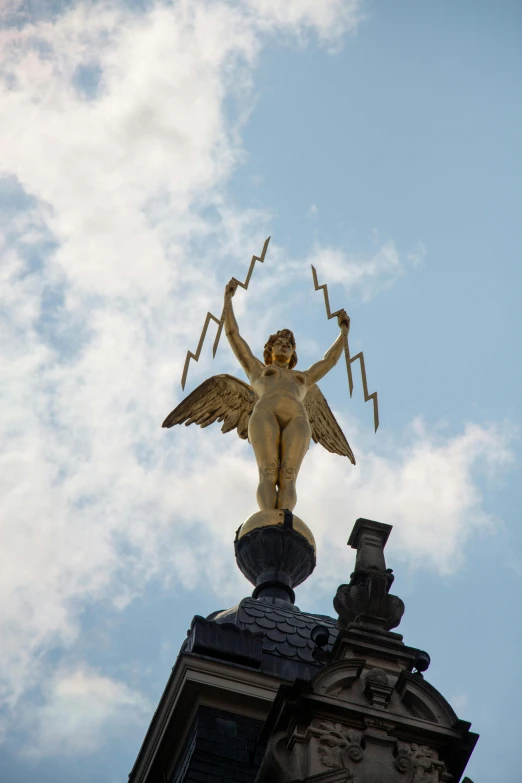 a statue stands atop the top of a building