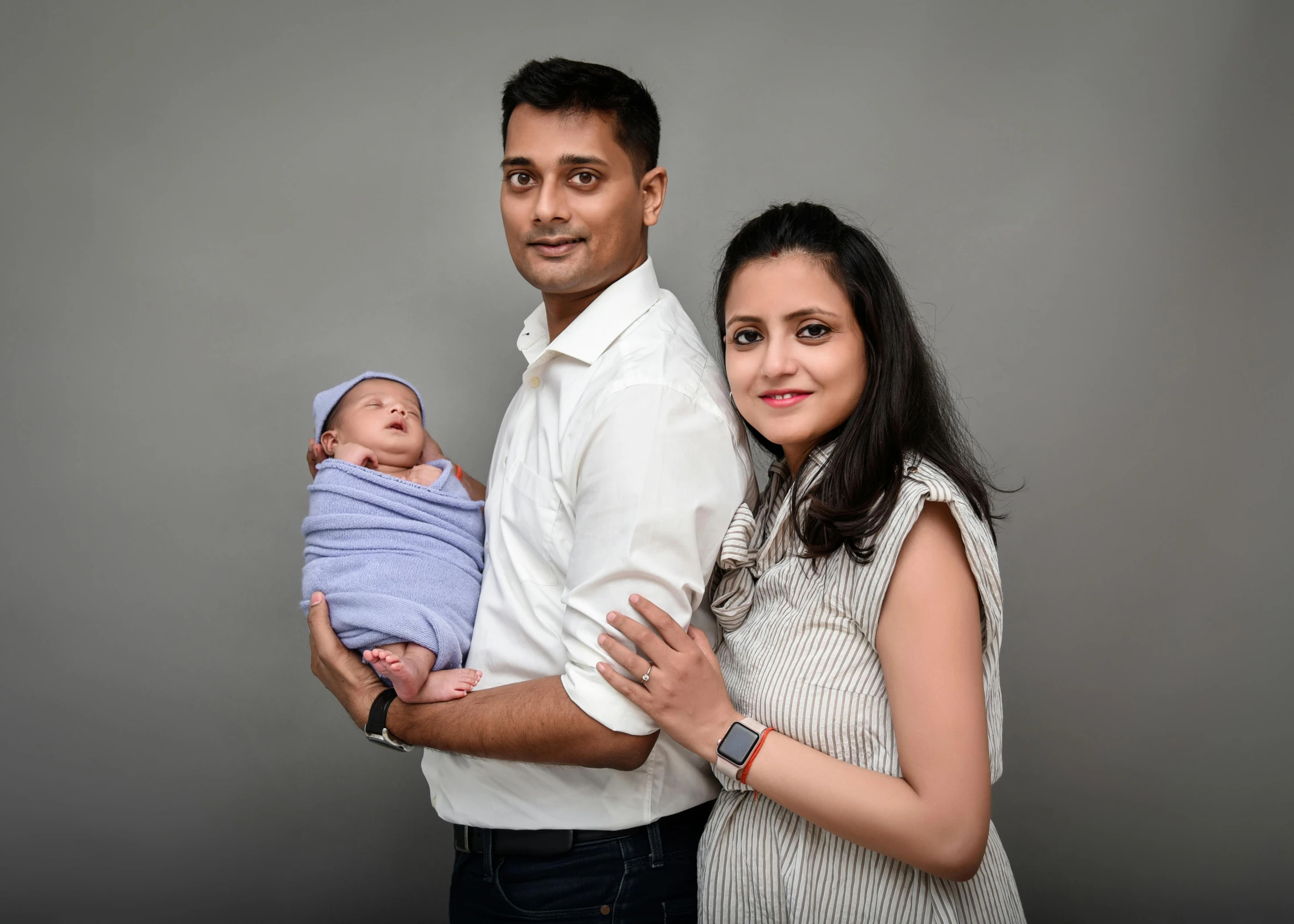 a man and woman posing for a pograph with a newborn boy