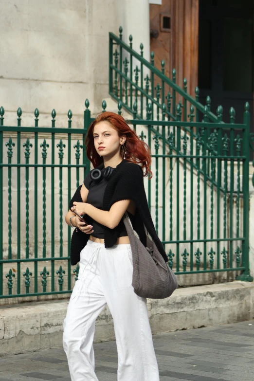 a woman wearing white pants is carrying a bag