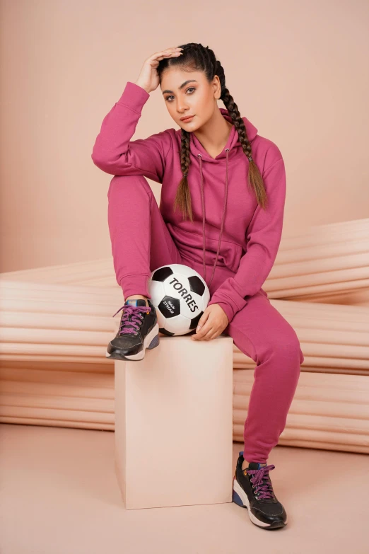 a woman sitting on top of a cube holding a soccer ball