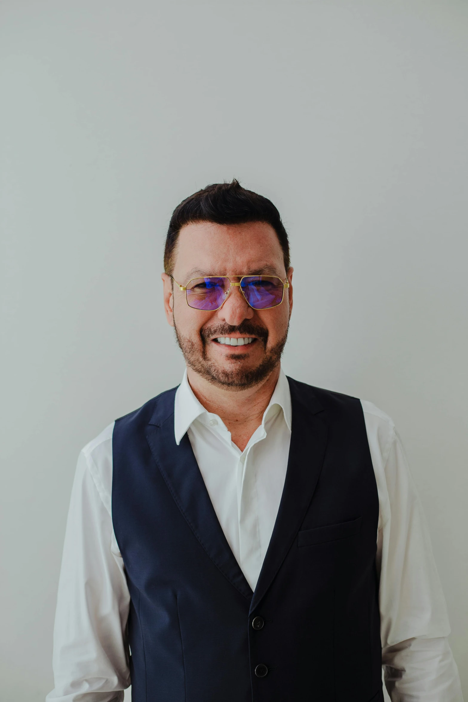 a man wearing sunglasses and vest standing