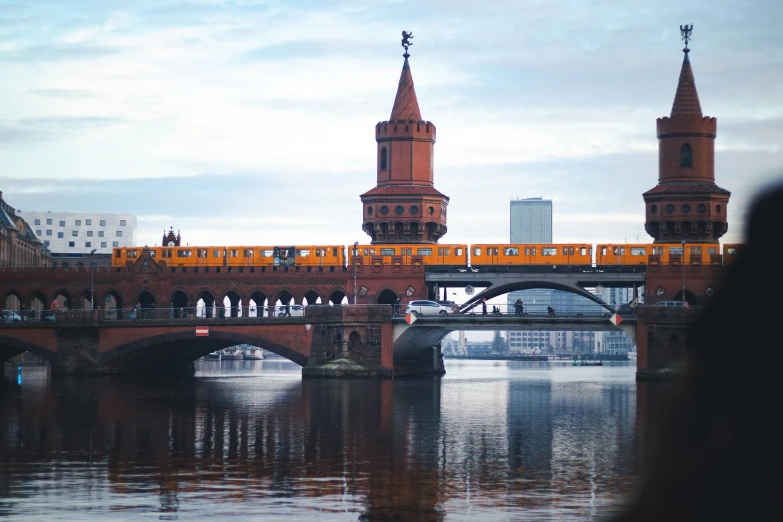 an orange train going over the bridge over the river