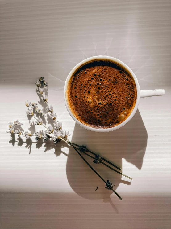 small white buds rest next to the bowl of coffee