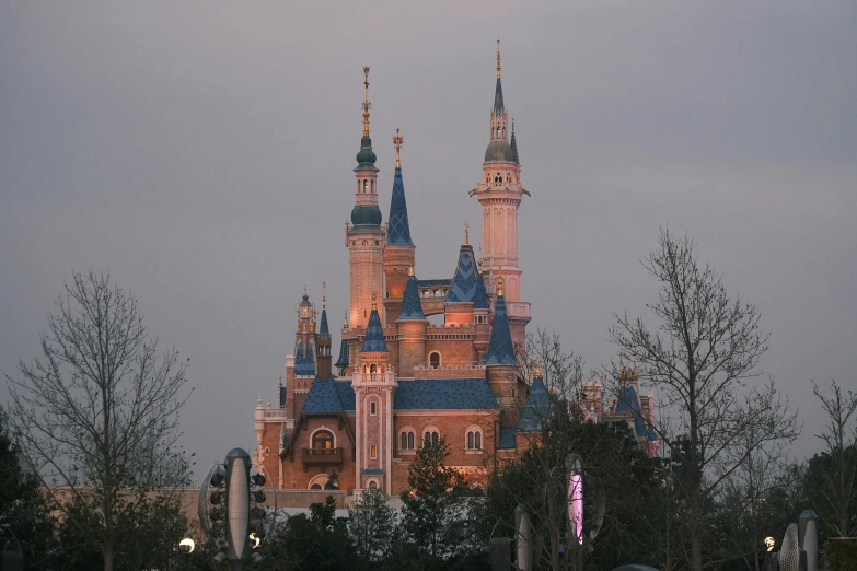 a large pink castle surrounded by trees and a sky line