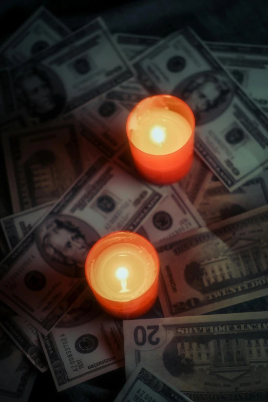 two orange candles with money in the background