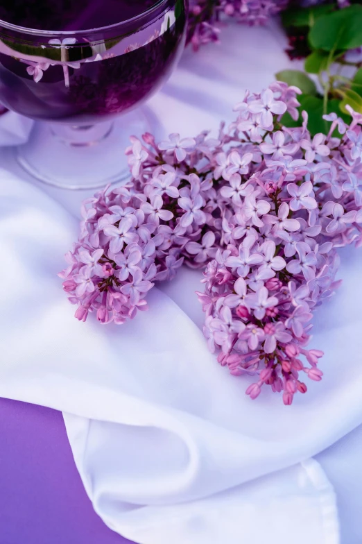 a small nch of lilac next to a purple glass with liquid