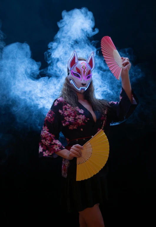 woman with an artistic mask on and holding a fan