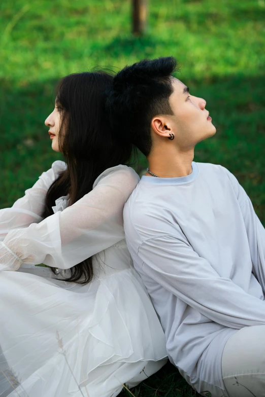 a couple wearing white clothes sitting next to each other on the grass