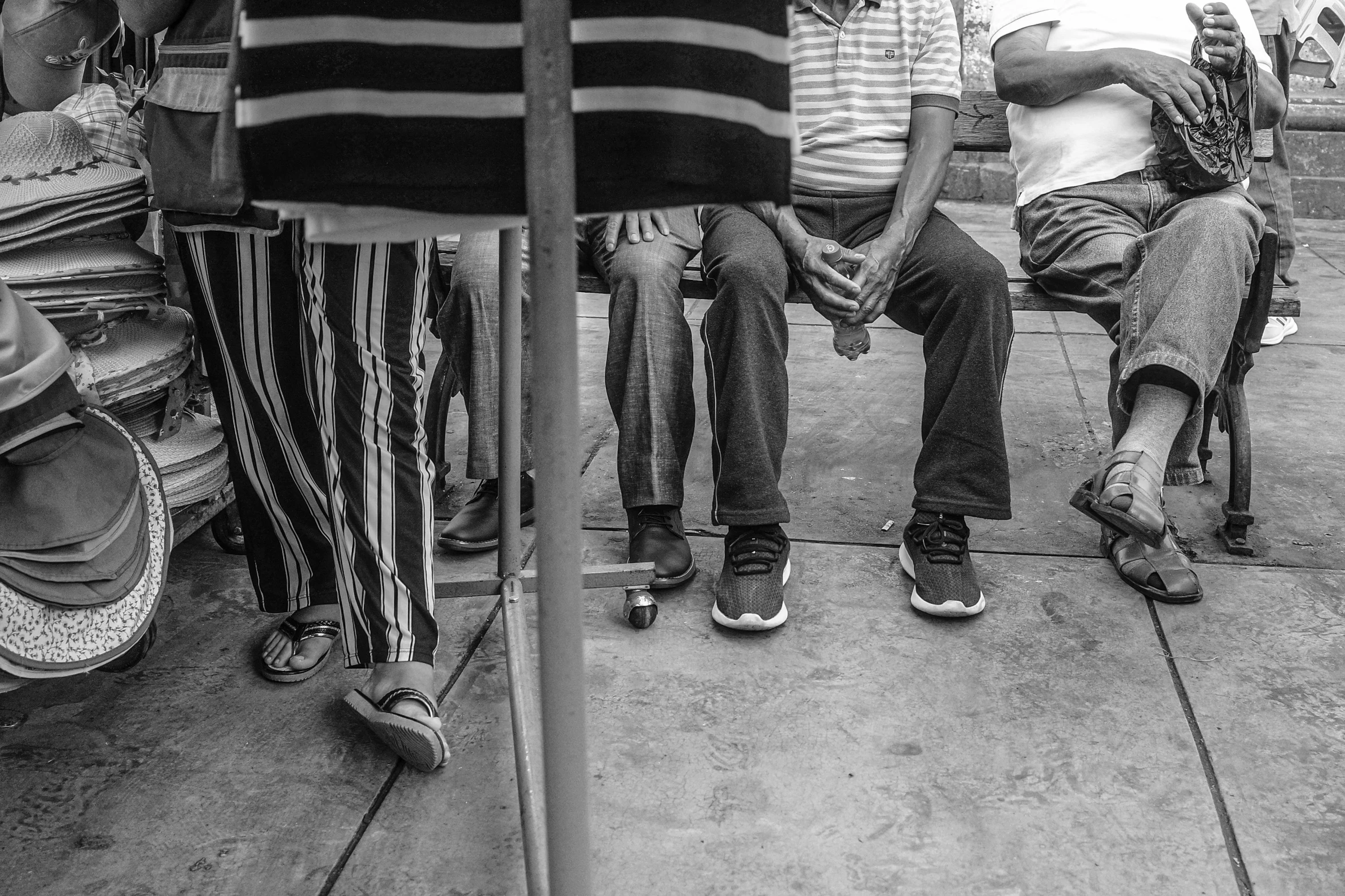 three men sitting on a bench one is holding the neck of another