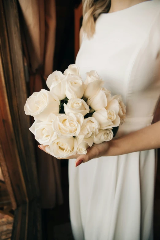 a white bouquet of roses are in front of a woman