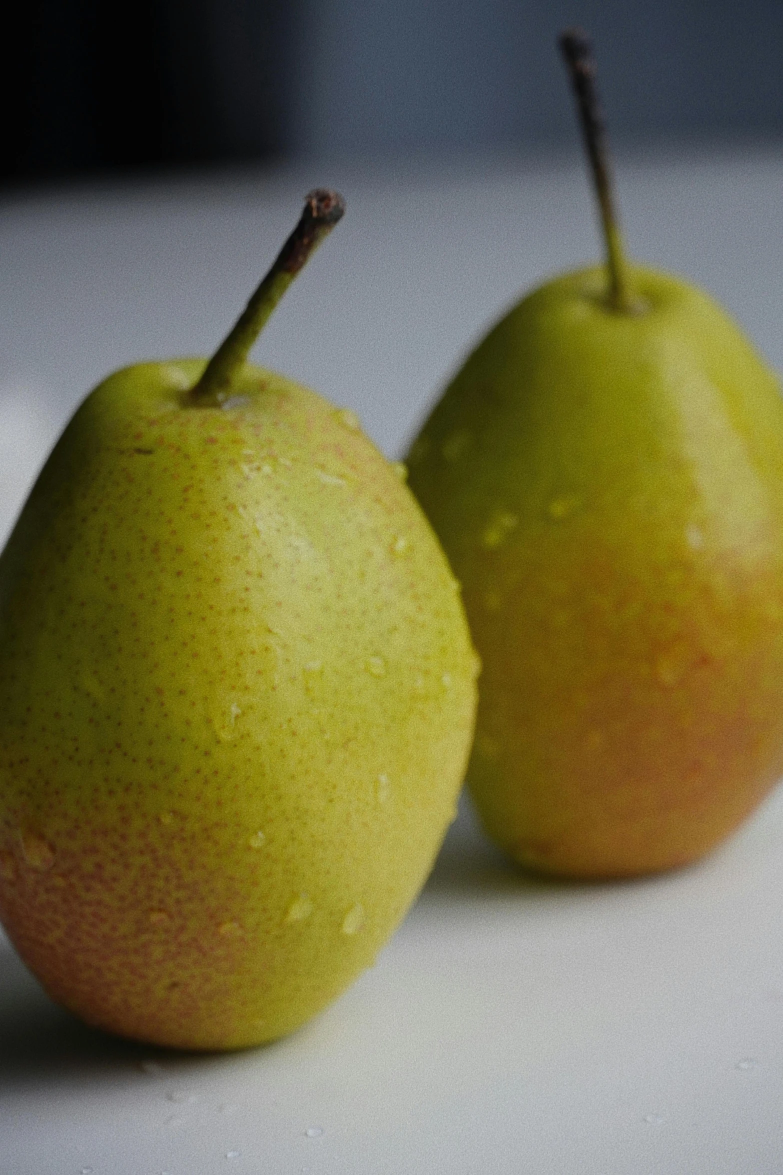 two pears are sitting side by side on a counter