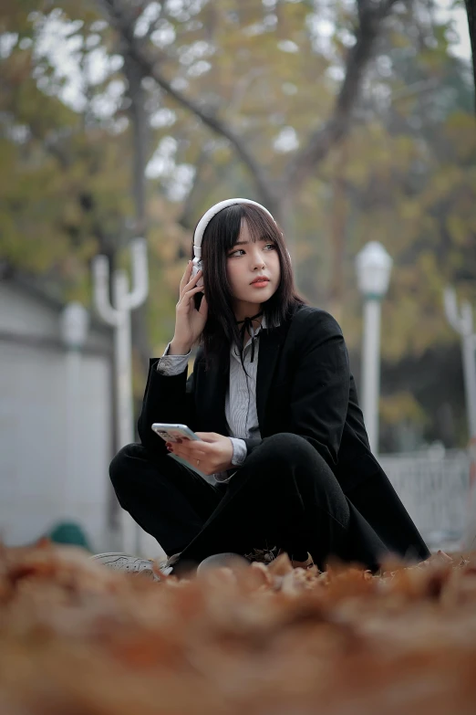 a woman sitting down on a hill with a cell phone in her ear