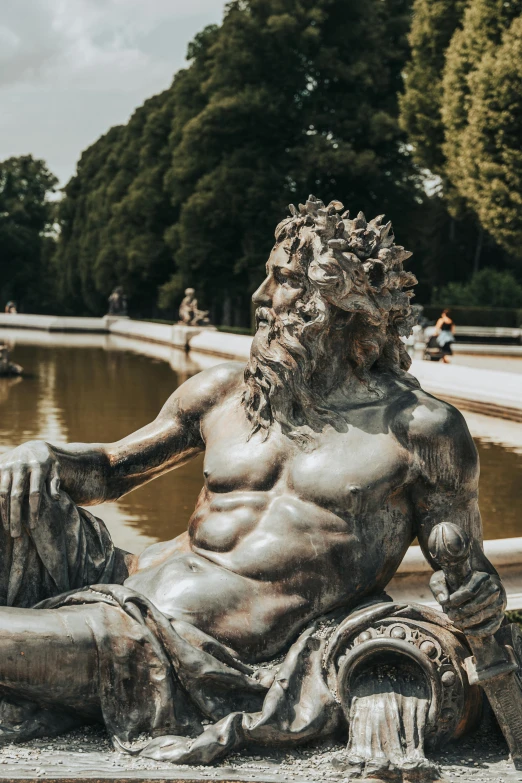 an image of the statue of a man sitting near a pond