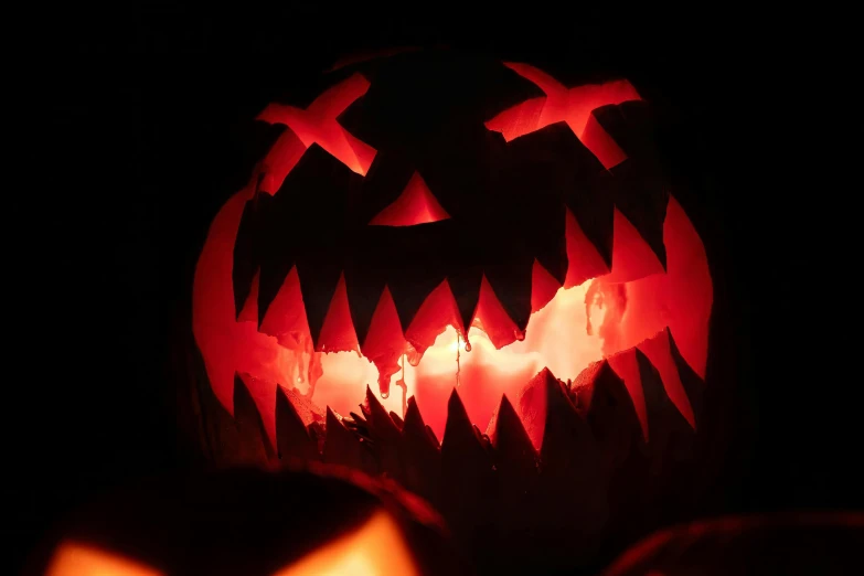 two carved pumpkins sit lit up in the dark