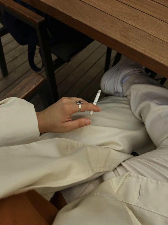 a person is holding their cigarette at the table