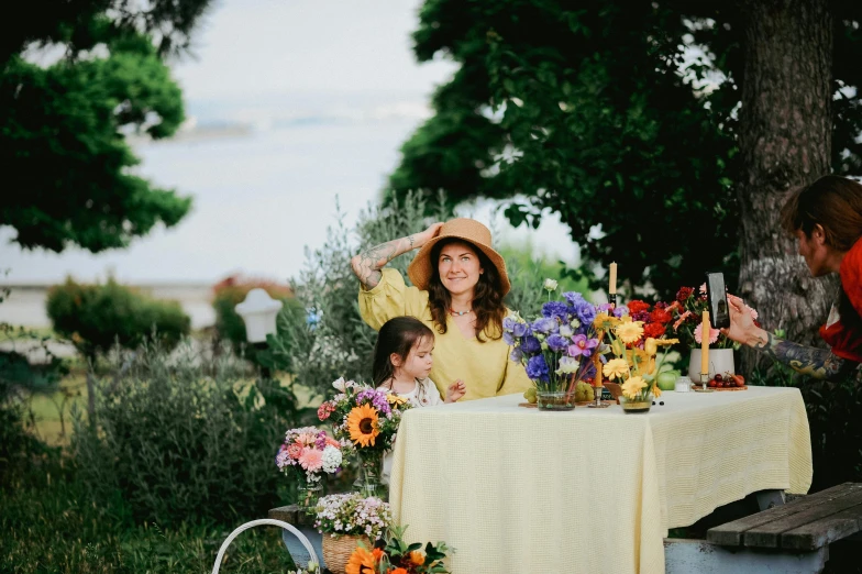 a woman sitting next to a table with flowers on it