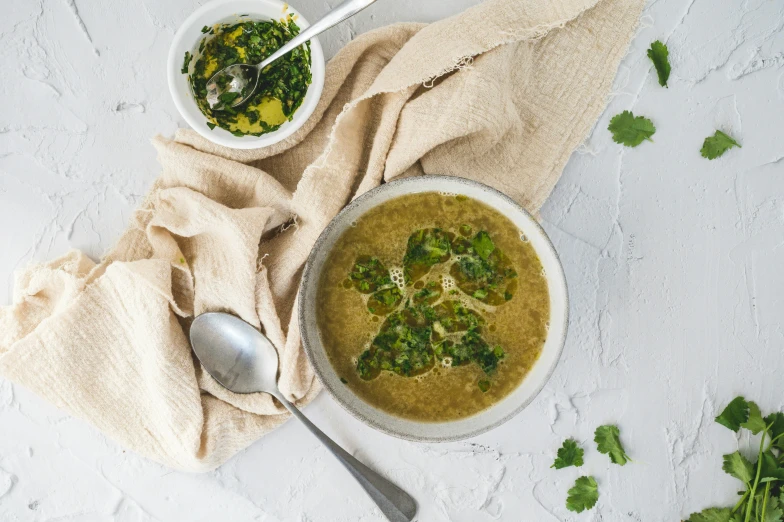 a plate of soup, two bowls of broccoli soup, and a towel