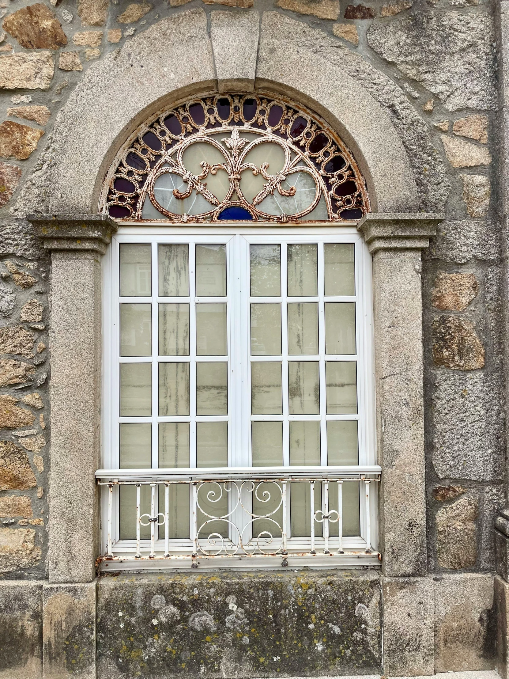 two windows with ornate windows on stone walls