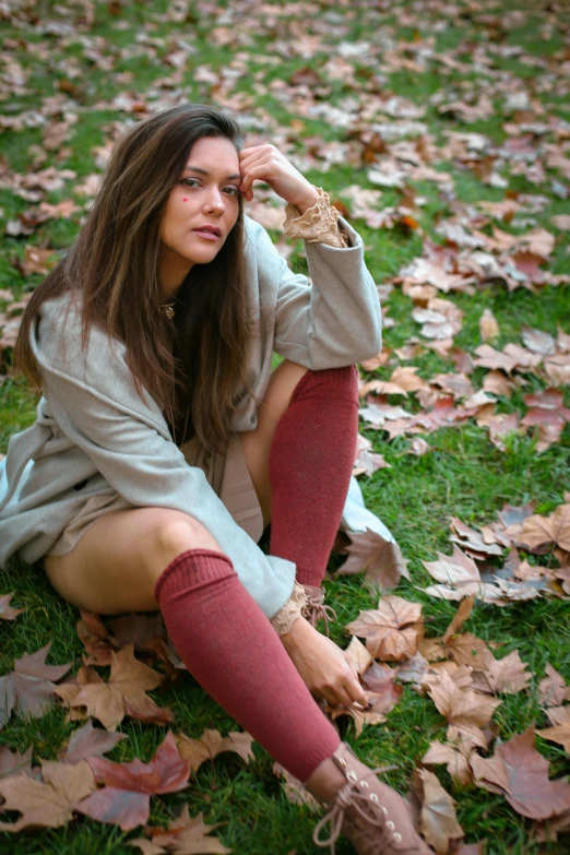 a girl sitting in the leaves looking concerned