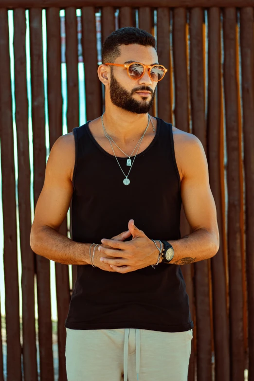 a man with a beard standing against a wooden fence