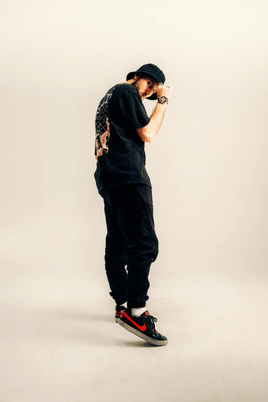 young man posing in black tracksuits with red and white cap