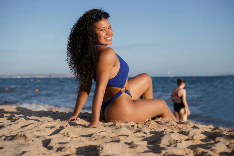 a woman wearing a blue bikini posing in the sand