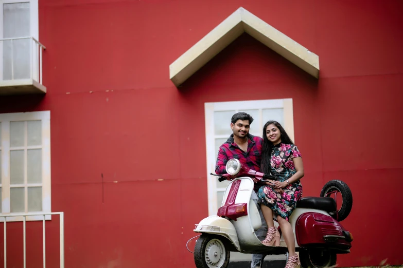 a man and woman sitting on a moped outside