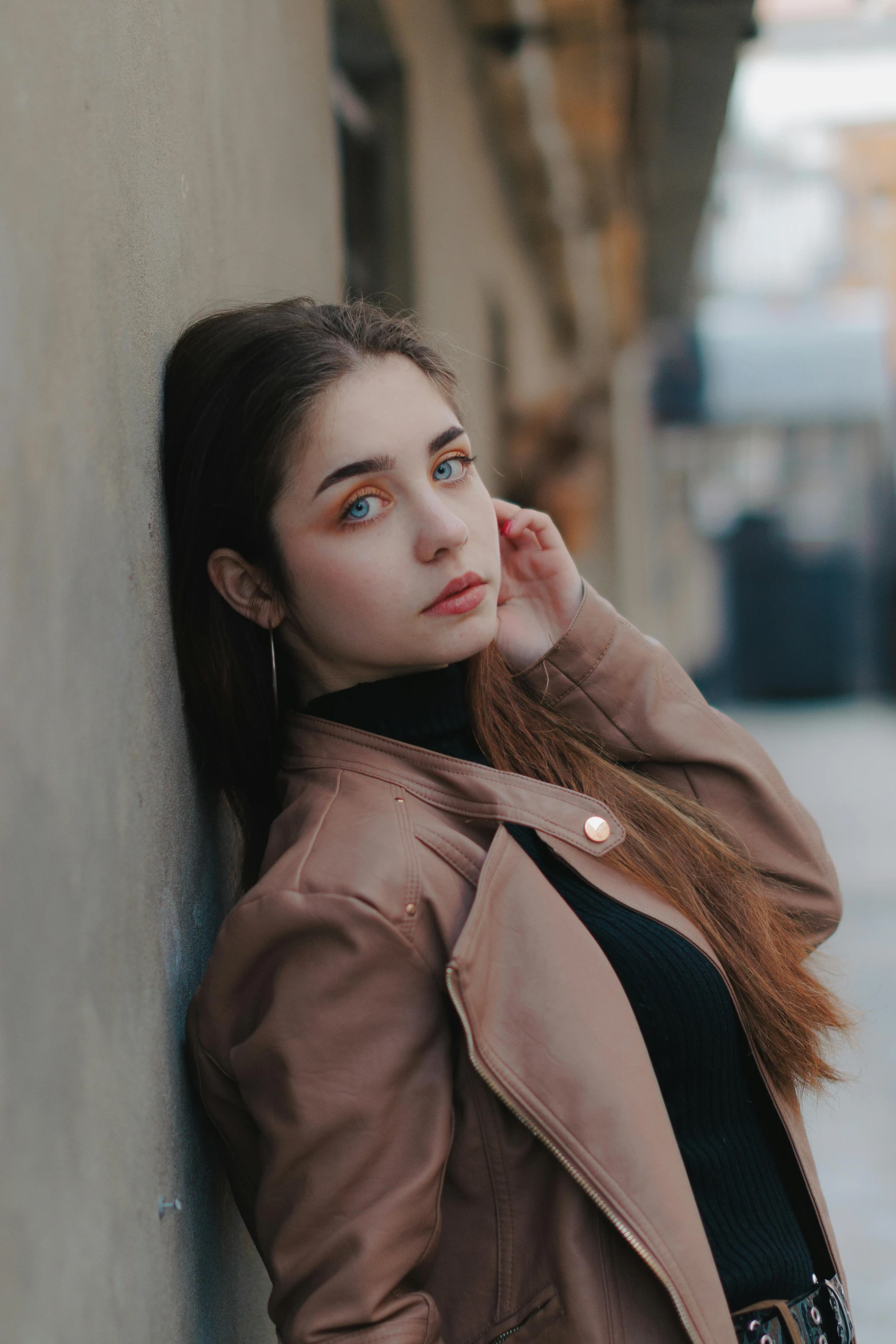 a beautiful young lady standing against a wall