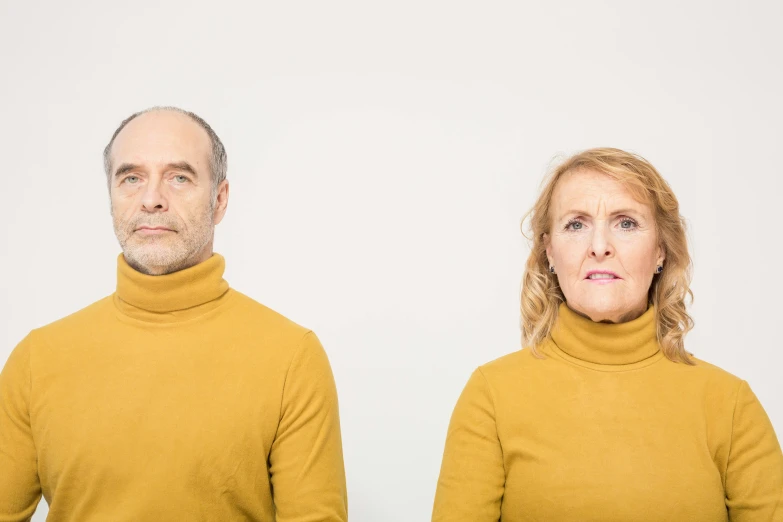 two people wearing sweaters standing together against a white background