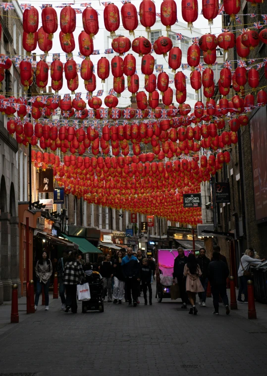 hanging red lanterns and chinese paper lanterns line a crowded sidewalk