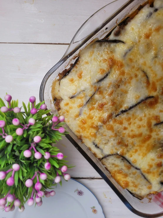 a close up of a casserole and flowers on a table