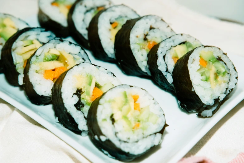 sushi is arranged on a plate on a cloth