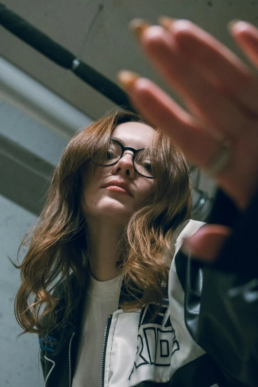 woman standing near window wearing glasses while another woman sits in the background