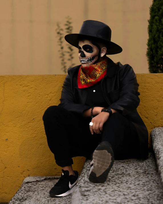 skeleton man sitting on yellow stone bench wearing hat and tie