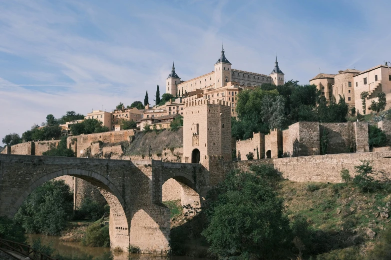 a stone bridge crossing over a river between buildings