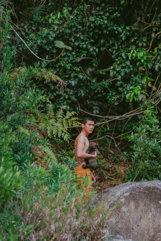 a boy wearing orange pants holds a monkey