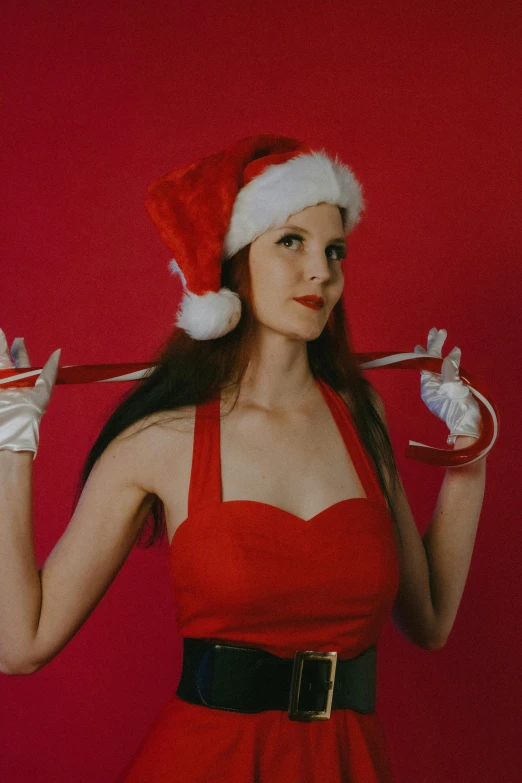 the woman wearing a santa hat is holding soing in her hand