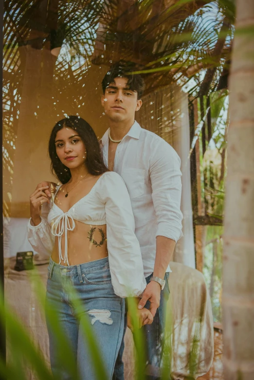 the couple poses for a po in front of their palm tree