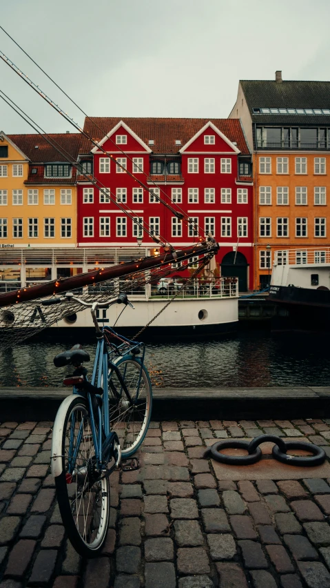 a bicycle parked on cobblestones next to a pier and buildings