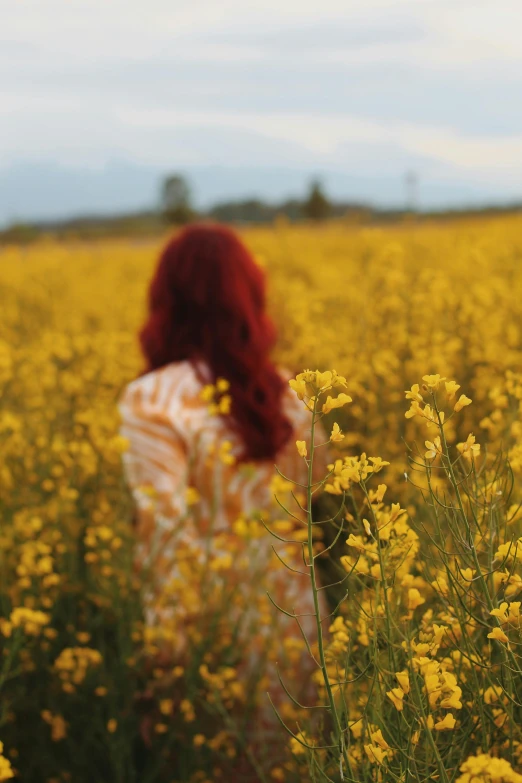 the woman is walking through a large field of flowers