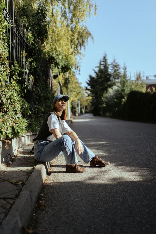 the girl is sitting on the curb and is leaning on her knees