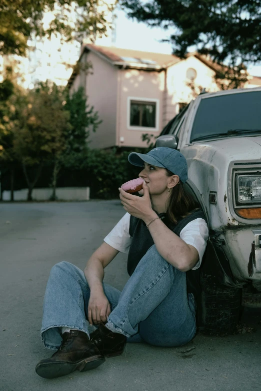 the girl is sitting by the truck eating a donut