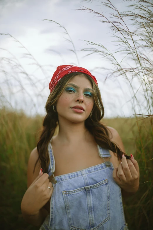 a girl wearing a bandana and blue eyeliners holding her hands over her shoulder