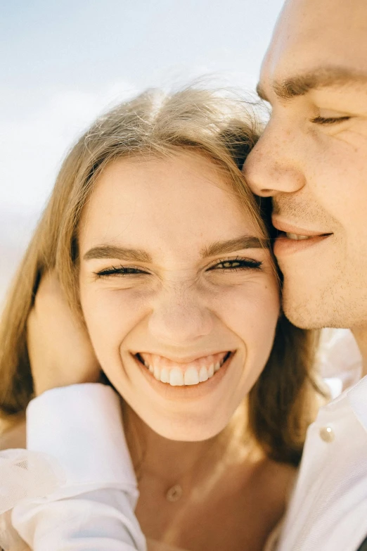 a man is emcing a woman who smiles broadly