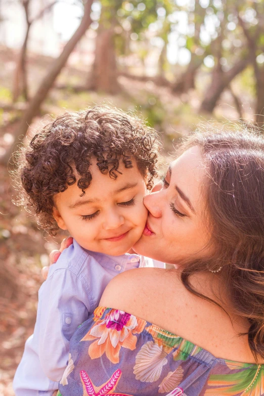 mother and son share a kiss while in the woods