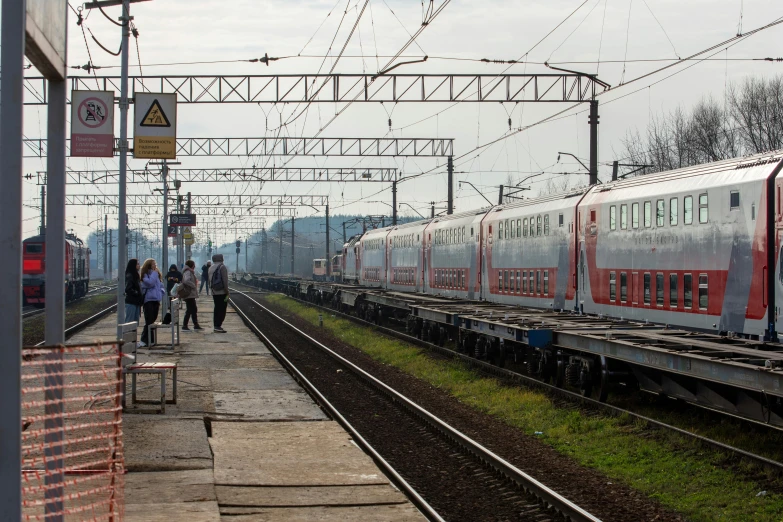 red passenger train stopped at a train station with passengers boarding