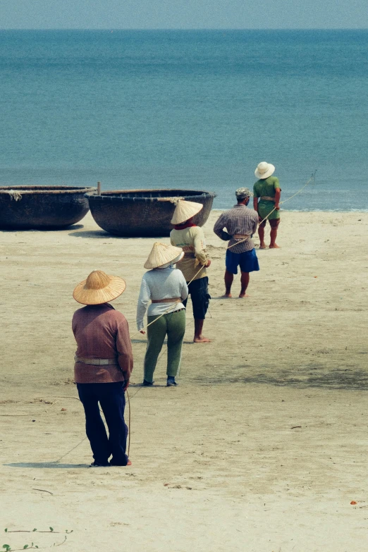 men and women walking on the beach near several small boats