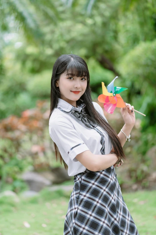an asian girl holding a pinwheel in a park